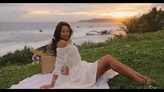 Happy Woman Enjoying a Picnic on a Green Grass Meadow Near a Beach During Sea Sunset