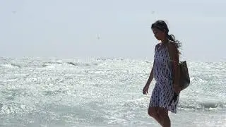 Slow motion shot of a young pregnant Asian woman walking on the beach.