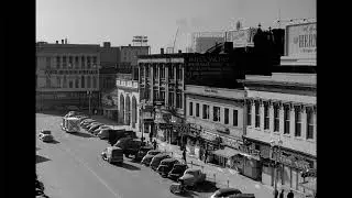 High-Angle View of Mid-Century City Street: Hotel Victoria, Vintage Cars & Pedestrians (1940s-50s)