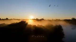 Drone slow motion flight over a misty lake at sunrise