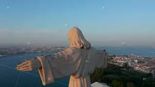 Big stone statue of Jesus illuminated by last sun rays of day. Drone camera flying behind Christ the