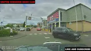 DARK COLOURED CAR DRIVER PULLS OUT IN FRONT OF THE CAMERA CAR DRIVER AS THEY TURN RIGHT