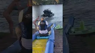 Boat pulls guy sitting on an inflatable sled down a water slide and into the lake!