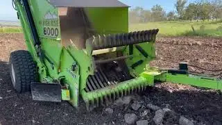 Rock Picker picking up a line of rocks to prepare the paddock for planting.