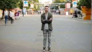Timelapse of Young man standing still at sidewalk in crowd traffic stream with people moving fast