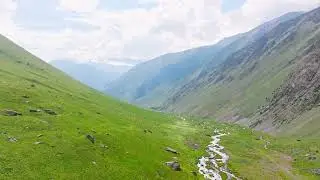 flying along picturesque mountain gorge with green slopes at sunny summer day in Kyrgyzstan