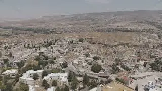 D-Log M. Urgup, Nevsehir, Turkey. Panoramic view of rocky cliff with ancient dwellings and modern...