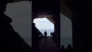 Silhouetted Figures Walking Through a Coastal Cave, Capturing the Serenity of the Sea and Sky