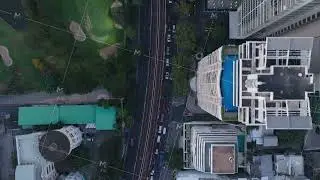 Aerial perspective following streets and railway line through Bangkok, Thailand. Modern buildings