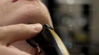 Close-up side view portrait of young bearded man getting beard grooming in modern barbershop in slow