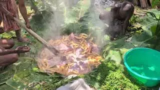 Hot stone cooking underground meat in banana leaves 