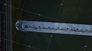 Top down aerial view from a tripod of a large tanker ship navigating on dark water of a river, next