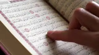 Close up shot of a Quran and a female person tracing the verses in the Quran with her finger