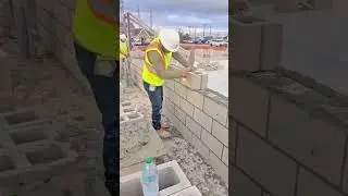 Worker in a Hard Hat and Safety Vest Laying Concrete Blocks (CMU) to Build an Exterior Wall