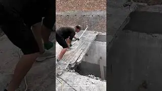 Construction workers breaking concrete slab with jackhammer