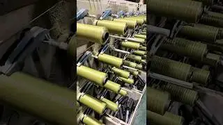 Winding yellow-green thread onto bobbins using textile machine