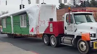 A flatbed truck carrying a modular home OVERSIZE LOAD 2/7/23