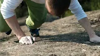 Man Carefully Taking Steps Up A Sheer Rock Face While Climbing Without A Rope Aerial