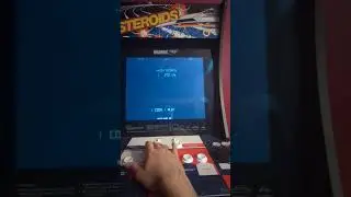 Playing Asteroids Arcade Game Shooting Meteors and flying saucers