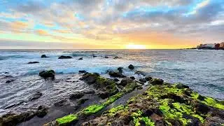 A breathtaking coastal sunset unfolds over the rugged rocks and gently rolling waves