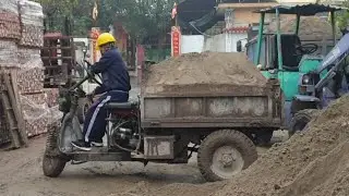 Three-wheeled tractor and excavator at work