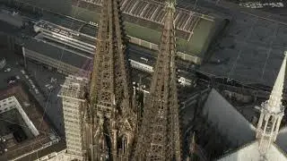 AERIAL: Close Up circling around Cologne Cathedral with Central Train Station in beautiful hazy