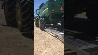John Deere S680 loading onto a Landoll 845HD-AG trailer.