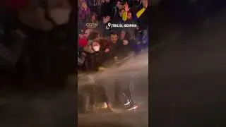 Protesters shield a woman waving an EU flag from a water cannon in Tbilisi, Georgia