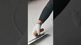 A worker smooths fresh cement with a trowel, creating an even textured surface