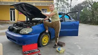 Girl repairs and restores a burned-out car in the middle of the road.