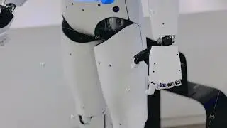 Futuristic white humanoid robot with blue chest moves its hands in a modern lab setting
