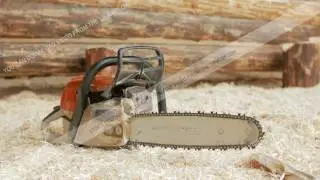 Chainsaw builder at the site of construction of a wooden house. Many sawdust and a part of the