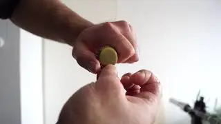 Old time strongman, , bending 2 crown corks (crown seals) with the left hand and a lateral grip