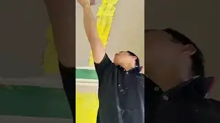 a man applies yellow plaster to a flat ceiling surface