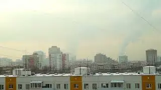 Город в дымке. Вид с балкона на многоэтажки и дым из труб