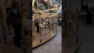 Abigail riding the carousel at The Woodlands Mall with grandma