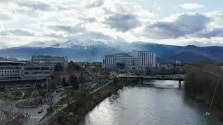 Panoramic cityscape of Grenoble nestled in French Alps, Isere river flowing past Hospital Michallon