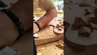 Carving intricate wood patterns with chisel amid scattered shavings and detailed figures