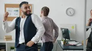 Dolly shot of creative young businessman dancing with colleagues at work then looking at camera