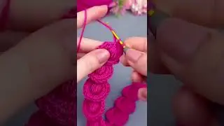 crocheting a vibrant pink yarn into a series of interconnected circles using a small metal hook tool