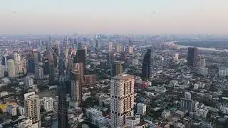 Tripod aerial view of Bangkok's sprawling metropolis during a hazy sunrise. Iconic skyline shows