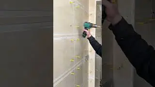 drilling several white tiles with a yellow power drill in a bright and sunny indoor room area today