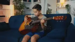 3465924359 preview Young boy practicing acoustic guitar play on sofa at home, musical hobby, art