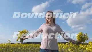 A happy girl walks among a rapeseed field on a warm spring day.
