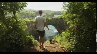 Static shot of a male tourist walking towards the cliff edge near famous arch and ocean cliffs of