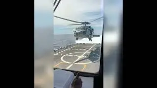 Navy Helicopter lands over moving ship