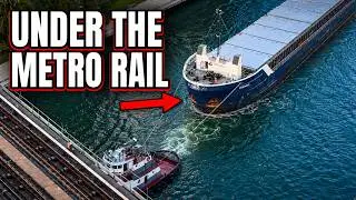 Tugboats Escorting A Cargo Ship Under The Metro Rail