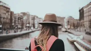 videoblocks lady with red backpack stands on river bridge girl in stylish hat with long hair and a p
