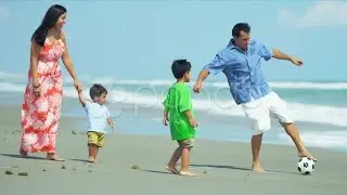 Latin American parents walking on beach playing football with children. Stock Footage