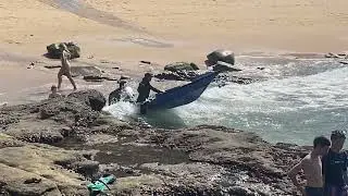 small boats surf launching through massive surf